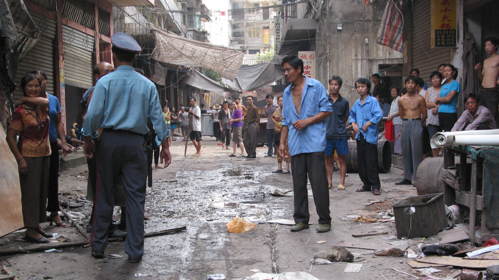 A photo of a street in an urban village, filled with men and women in work clothes